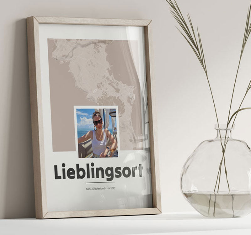 Personalisiertes Poster Lieblingsort mit Bild im Holzrahmen auf Tisch neben Vase